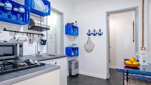 A modern kitchen with a gas stove, microwave, and blue storage shelves.