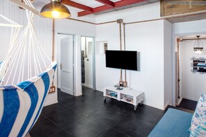 A room with a hammock, a TV on a stand, a door leading to another room, and a blue mat on the floor.