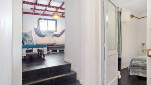 A bedroom with a bed, a window, a staircase, and a door leading to another room.