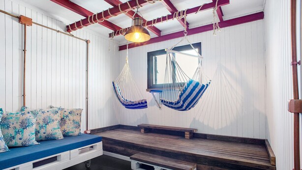 A room with a wooden bench, a hammock, and a ceiling light fixture.