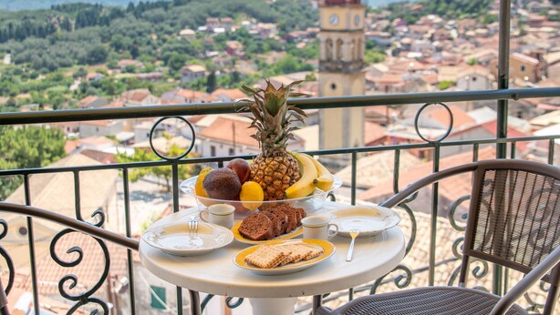 Ein Balkon mit Frühstückstisch, ein Glockenturm und Blick auf eine Stadt.