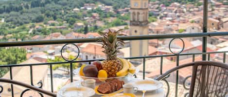Un balcon avec une table préparée pour le petit-déjeuner, un clocher et une vue sur la ville.