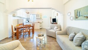 Un'ampia zona giorno con tavolo da pranzo, divano e angolo cottura sullo sfondo.