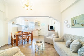 Een ruime woonkamer met een eettafel, bank en een keuken op de achtergrond.