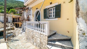 Un edificio con una scala in pietra, un balcone con ringhiere bianche e una finestra con persiane verdi.
