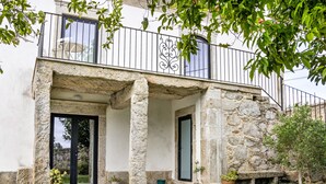 Un bâtiment en pierre doté d’un balcon, de plantes en pot et d’une porte.