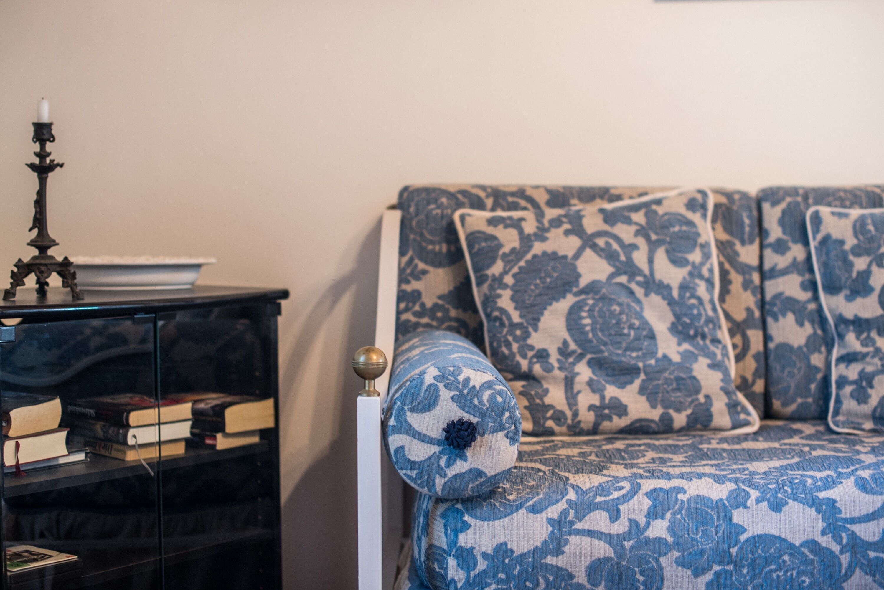 A room with a sofa, a side table with a candelabra, and a bookshelf.