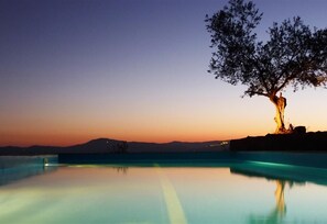 Un área de piscina tranquila con un árbol y montañas a lo lejos.