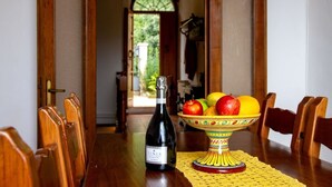 Een eettafel met een fles wijn, een fruitschaal en houten stoelen.