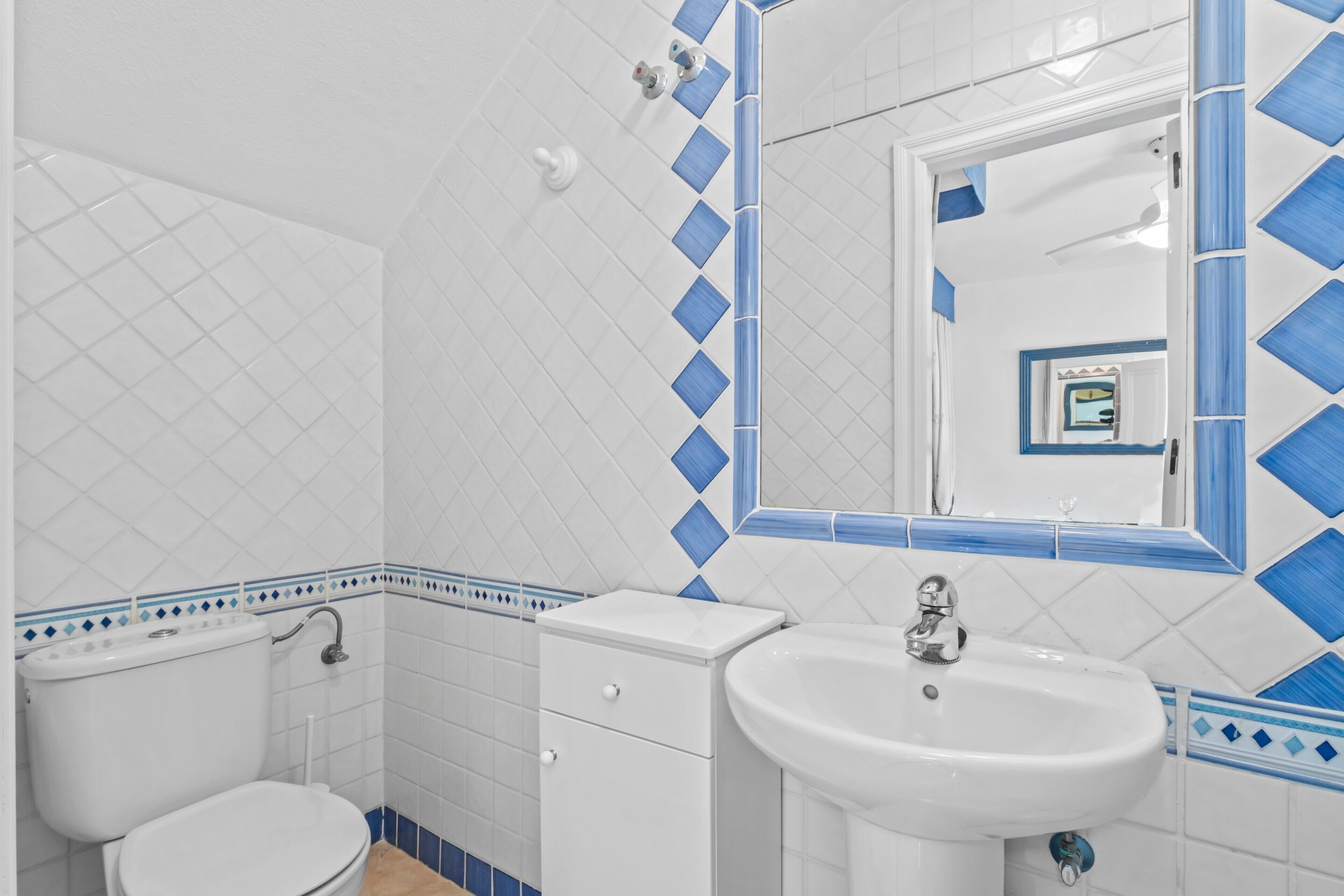 Een badkamer met toilet, wastafel en spiegel.