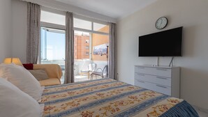 A hotel room with a bed, a TV, a dresser, and a balcony with chairs. - Studio Marina view apartment with Sea View & Wi-Fi (Fuengirola)