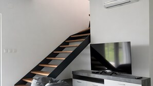En moderne stue med trappe, et fladskærms-tv og indbyggede skabe.