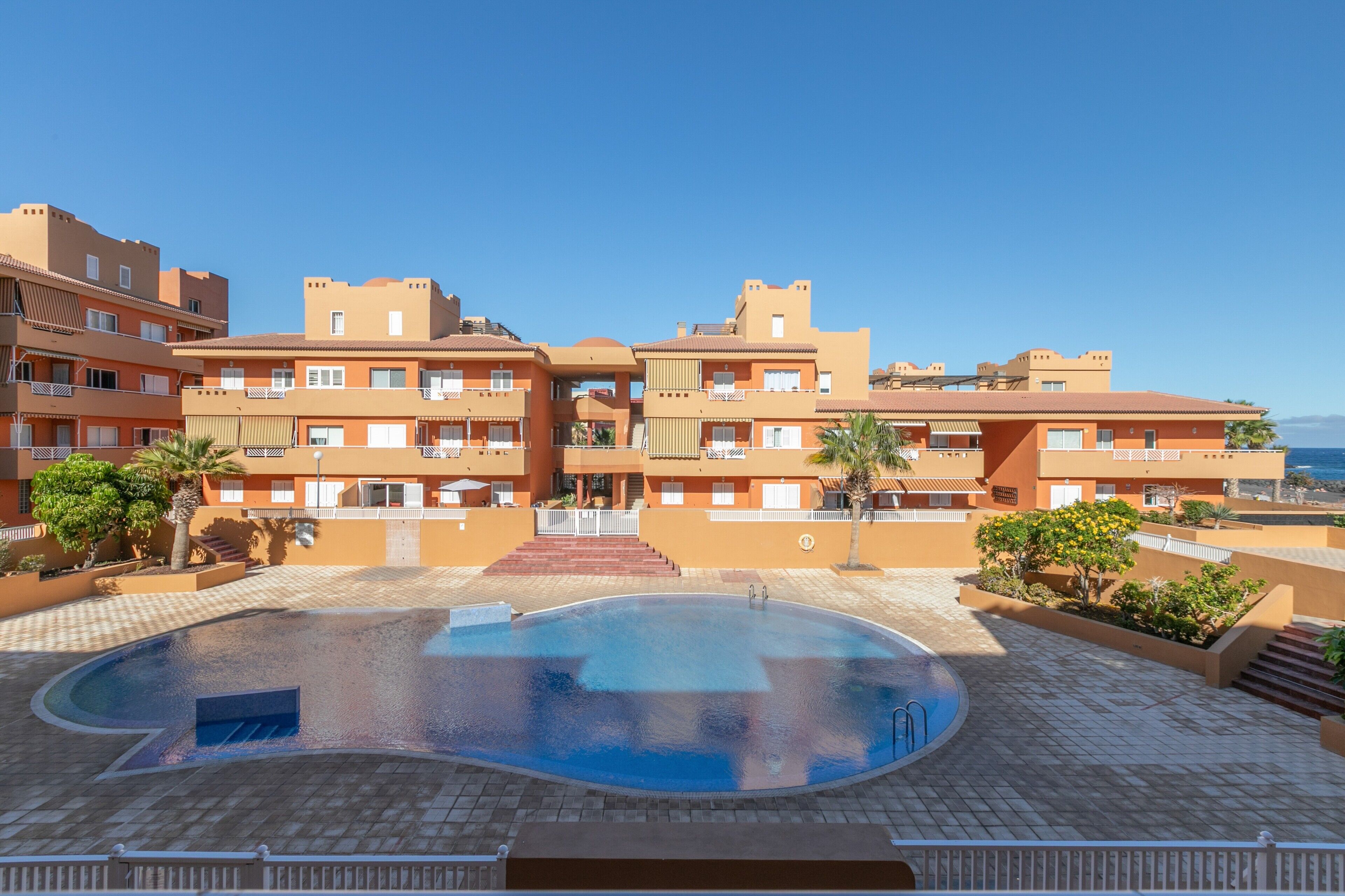 Un hotel con piscina, varios balcones y vistas al mar.