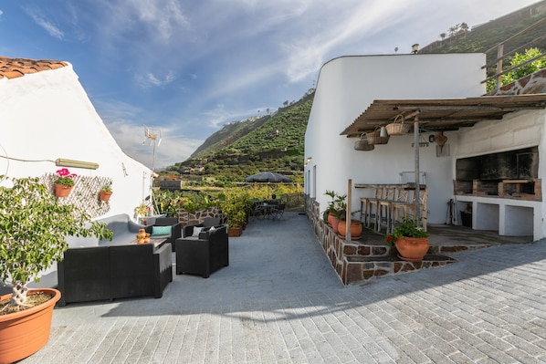 Une terrasse extérieure aménagée avec des sièges, des plantes en pot et une vue sur une colline.