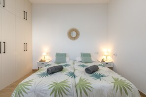 Une chambre à coucher comprenant un lit, deux tables de chevet, un miroir fixé au mur et une armoire.