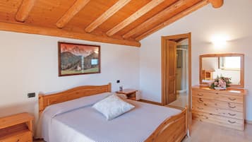 A bedroom with a wooden bed, a nightstand, a dresser, a mirror, and a painting on the wall.