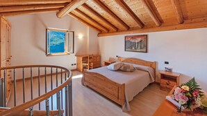 Un dormitorio con techo de madera, una cama, una mesita de noche, un aparador y una ventana con vistas.