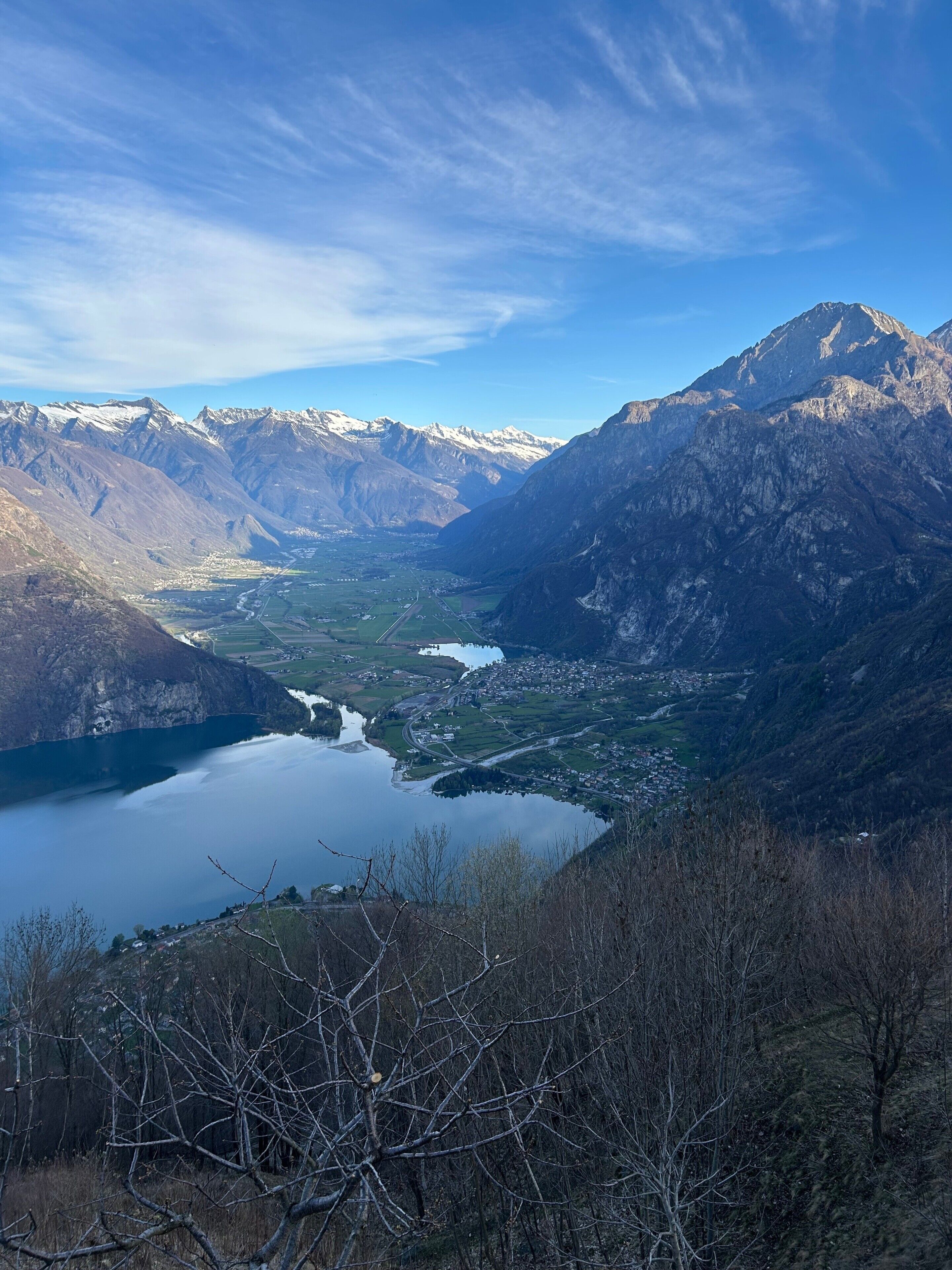 Paisatge de muntanya amb un llac, una vila i cims nevats.