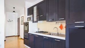 Una cocina moderna con gabinetes oscuros, un lavamanos de acero inoxidable y una estufa a gas.