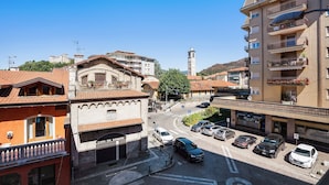 Vista de la calle con edificios, una torre del reloj y coches aparcados.