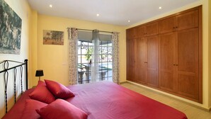 Une chambre à coucher avec un lit, une armoire, une fenêtre avec des rideaux et un tableau au mur.