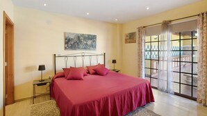 Une chambre à coucher avec un lit, deux tables de chevet, une fenêtre avec des rideaux et un tableau au mur.