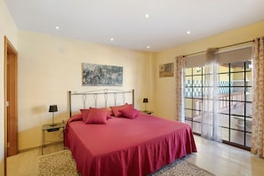 Un dormitorio con una cama, dos mesitas de noche, una ventana con cortinas y un cuadro en la pared.