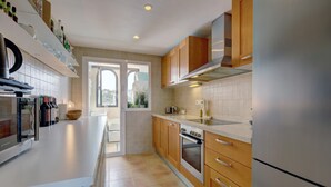 A modern kitchen with a stainless steel refrigerator, wooden cabinets, a built-in oven, and a large window. - Apartment '2 Bed-rooms with A View' with Sea View, Wi-Fi and Air Conditioning (Benahavís)
