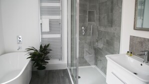 Ein modernes Badezimmer mit freistehender Badewanne, einer Duschkabine und einem weißen Waschtisch.