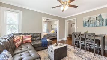 A living room with a sectional sofa, a coffee table, and a dining area with a table and chairs.