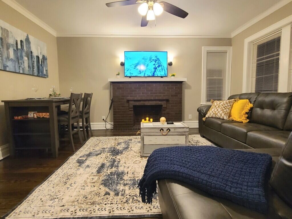 Een woonkamer met een open haard, een televisie, een bank en een eethoek.