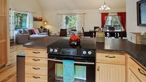 A modern kitchen with a built-in oven, a countertop with a kettle, and wooden cabinets.