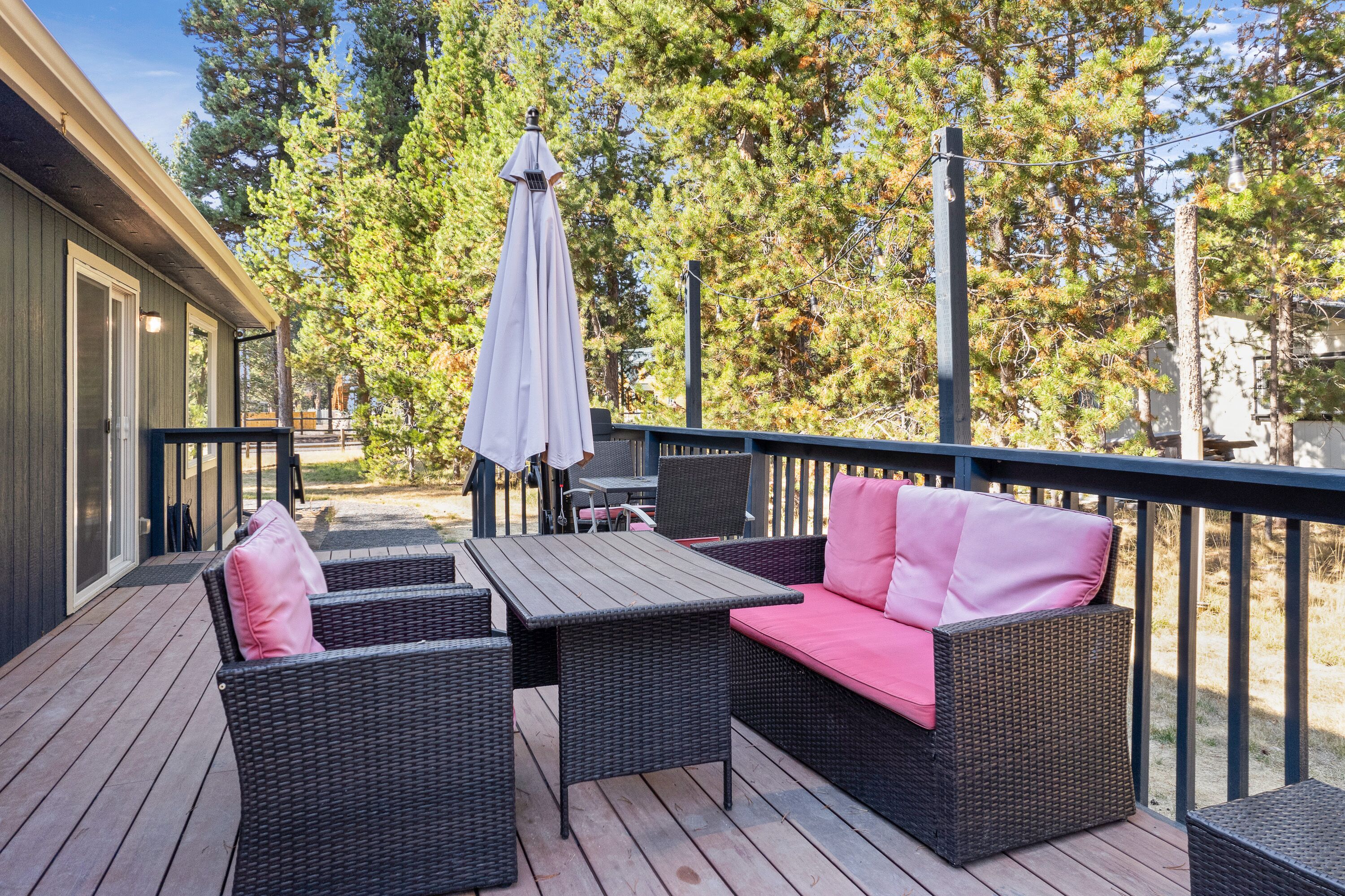 Una terraza con muebles de mimbre, incluyendo una mesa y dos sofás, y una sombrilla.