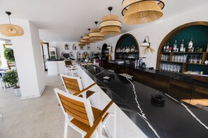 A modern bar area with a long counter, multiple seating options, and a variety of bar tools and bottles.