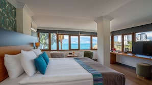 A hotel room with a large bed, a TV, a small table, and a view of the sea. - Qinn Hotels (Antalya)