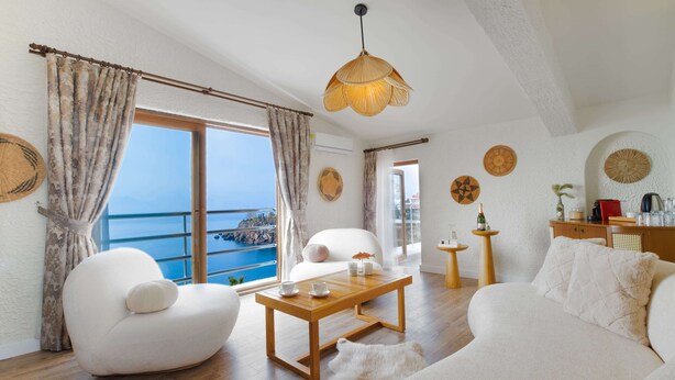 A modern living room with a wooden coffee table, white sofas, and a view of the sea. - Qinn Hotels (Antalya)