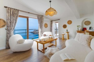 A modern living room with a wooden coffee table, white sofas, and a view of the sea.