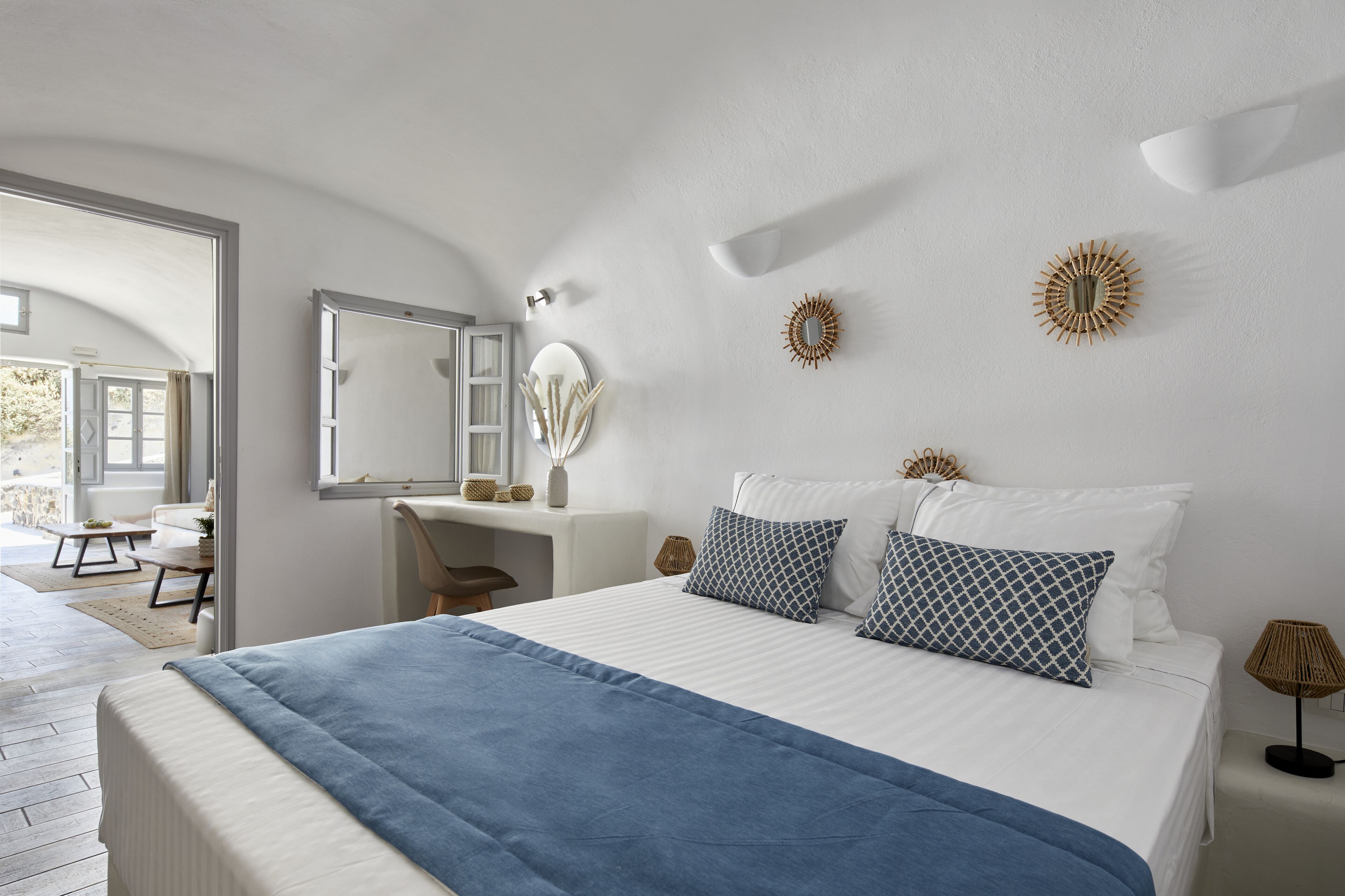 A bedroom with a bed, bedside tables, a desk, and a mirror.