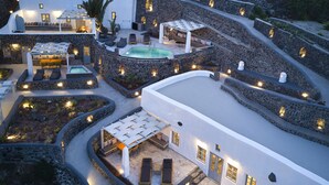 A resort with multiple outdoor seating areas, a swimming pool, and stone walls. - El Verano Suites (Santorini)