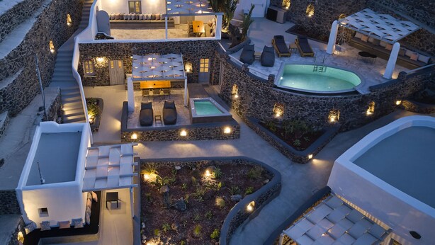 A modern villa with a pool, outdoor seating, and stone walls. - El Verano Suites (Santorini)