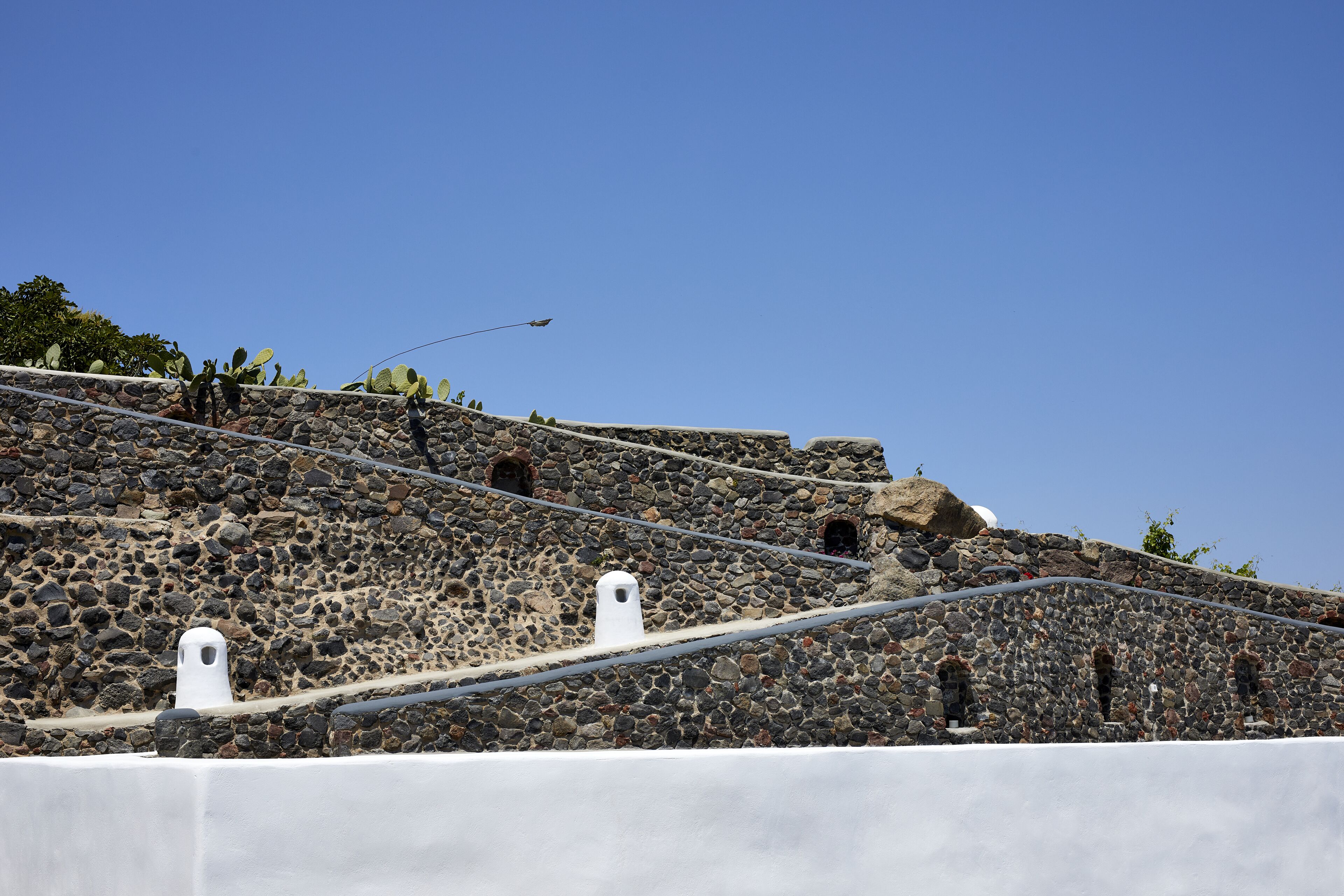 Una escalera de piedra con ventanas arqueadas y barandilla blanca.