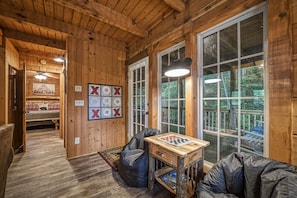 A cozy cabin interior with wooden walls, a game table, and a view of the outdoors.