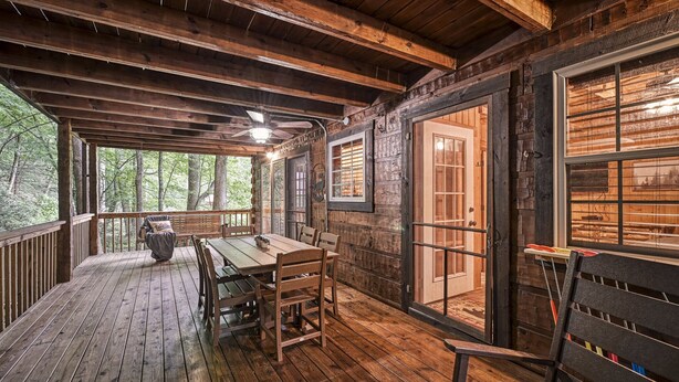 A wooden deck with a table and chairs, a ceiling fan, and a view of the forest. - #1 KID'S CABIN!! JUST RENOVATED| CREEK| MINI GOLF⛳️PIRATE PLAY SHIP🏴‍☠️ HOT TUB (Cosby)