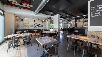 Un ristorante moderno con condotte a vista, tavoli e sedie in legno.