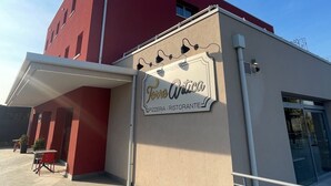 Un edificio con fachada roja y un cartel que dice 'Torre Antica Pizzeria - Ristorante'.