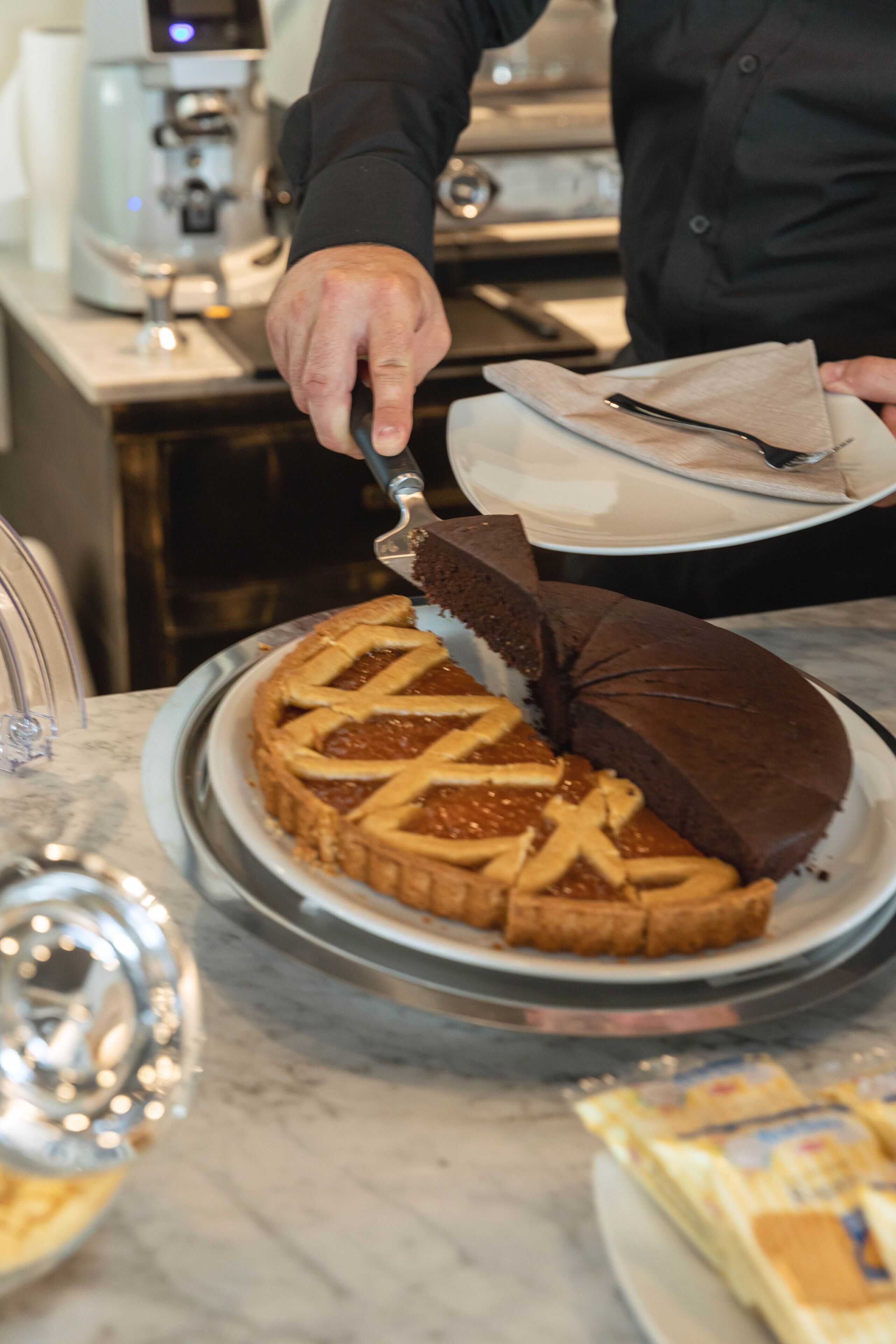 A person cutting a pie with a lattice crust on a metal serving tray.
