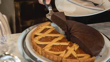 Una persona cortando un pastel con costra enrejada sobre una bandeja metálica.
