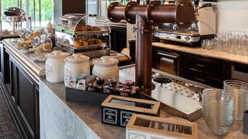 A breakfast bar with a coffee machine, tea dispensers, and a variety of food items.