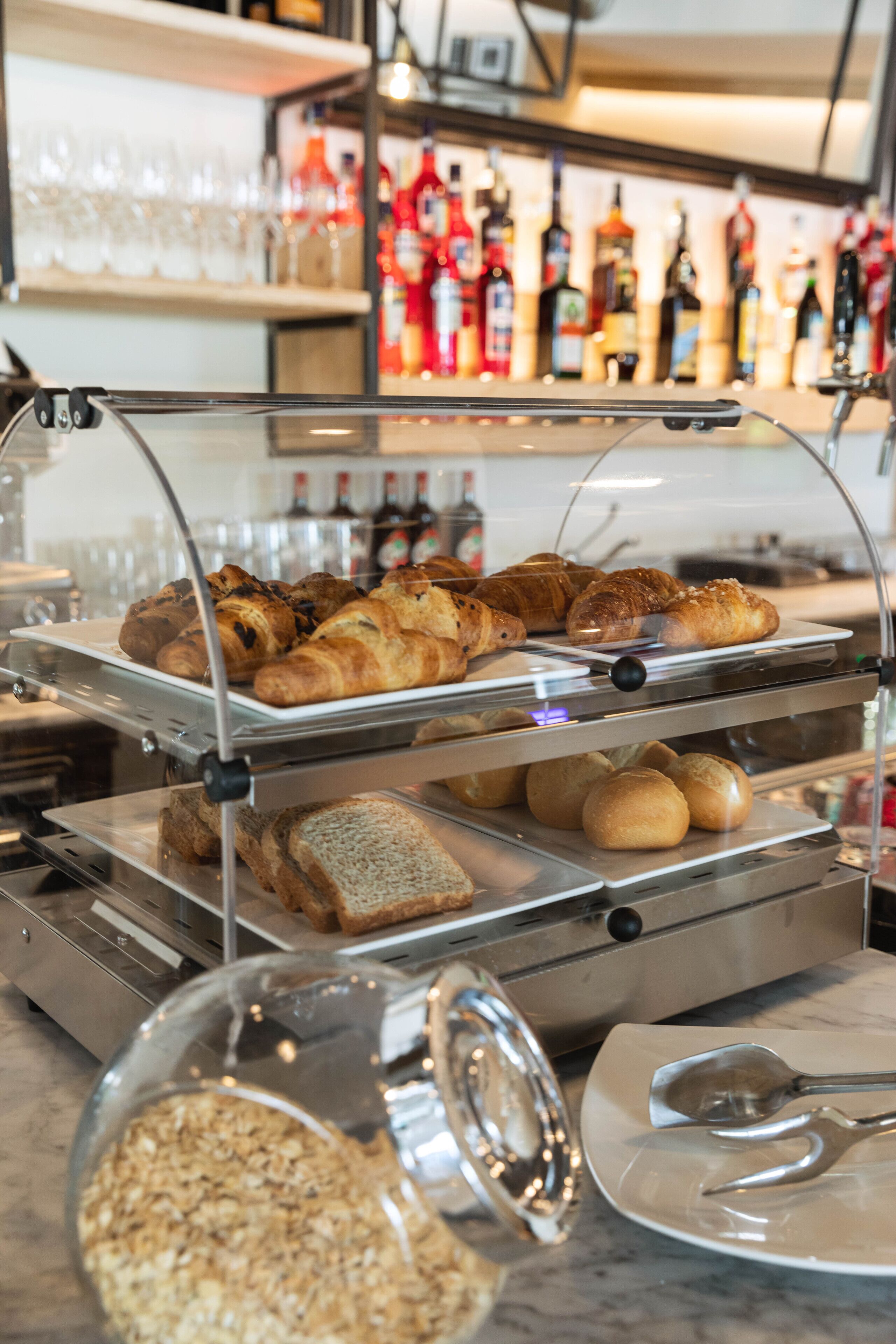 A bakery display with various baked goods and a glass jar of granola.