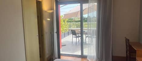 A hotel room with a bed, a sliding glass door leading to an outdoor patio with a table and chairs.